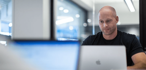 Nelnet CyberSecurity protects data for associates and business lines. A Nelnet associate sits at a laptop in a room full of other computers
