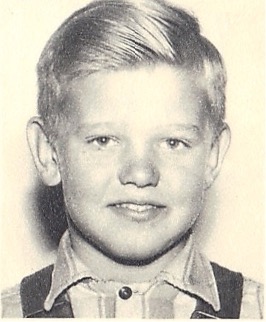 Black-and-white portrait of a young child with short hair, smiling and facing the camera.