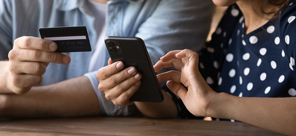 A person holding a credit card while another is holding a smartphone
