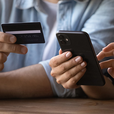 A person holding a credit card while another is holding a smartphone